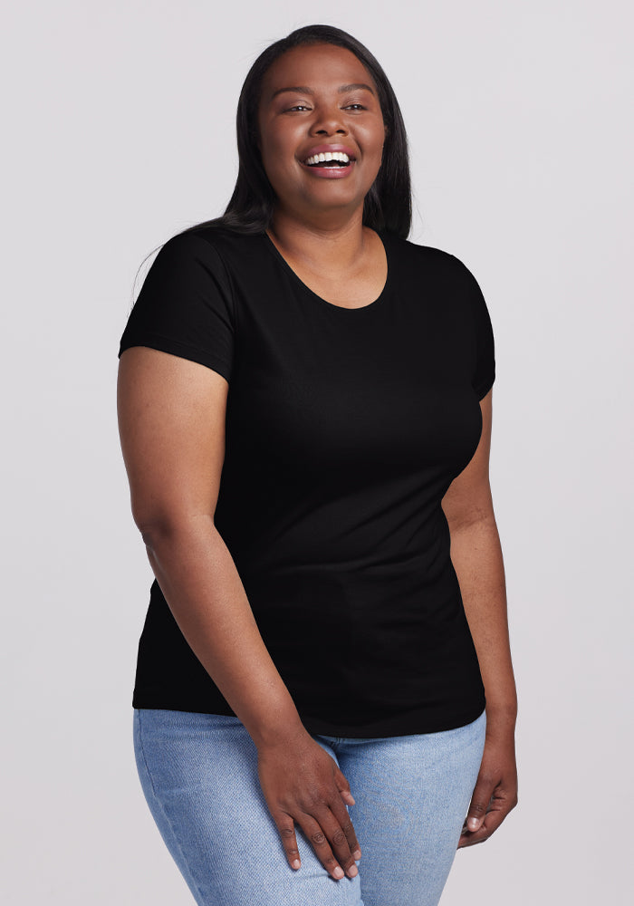 A woman with long dark hair smiles in front of a light background, wearing the ultra-soft Woolx Addie Crew Neck in black paired with light blue jeans. | Le'Quita is 5'11", wearing a size XL