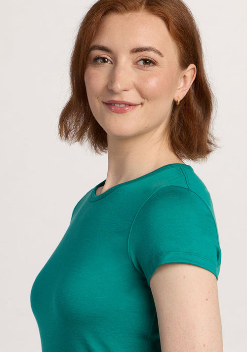 Smiling woman with short auburn hair wears the Woolx Addie Crew Neck in Cabana Crush, posing against a light background.