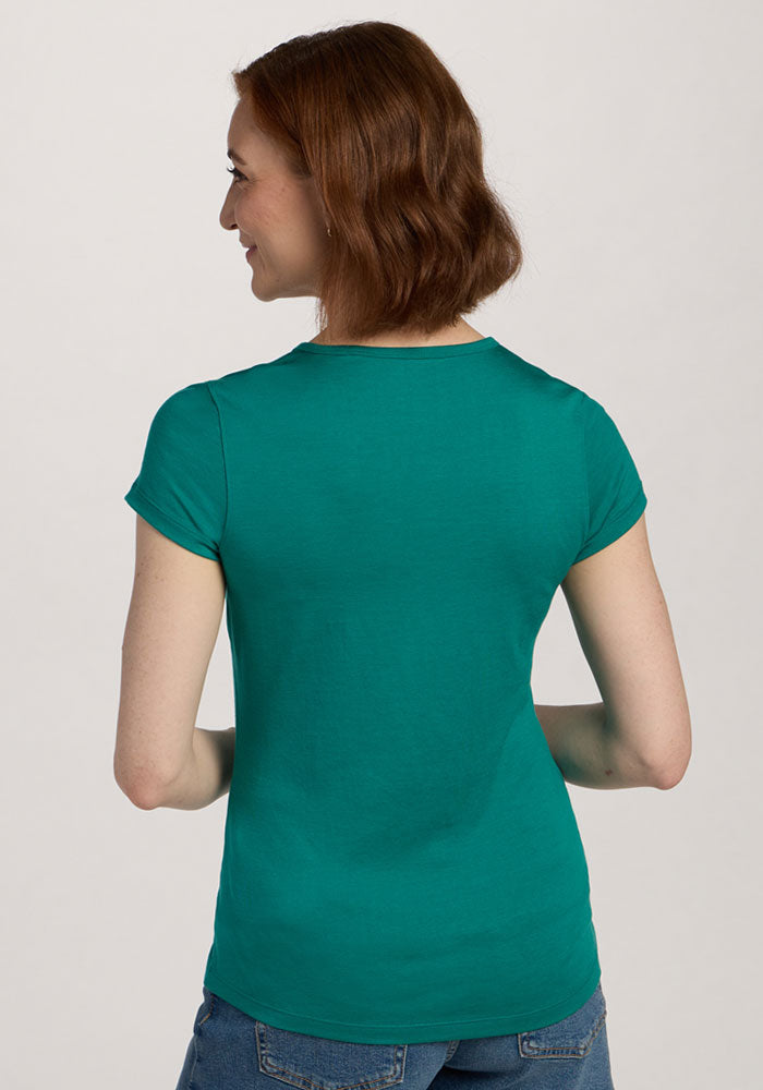 A woman with short brown hair wears the Woolx Addie Crew Neck - Cabana Crush, standing with her back to the camera.