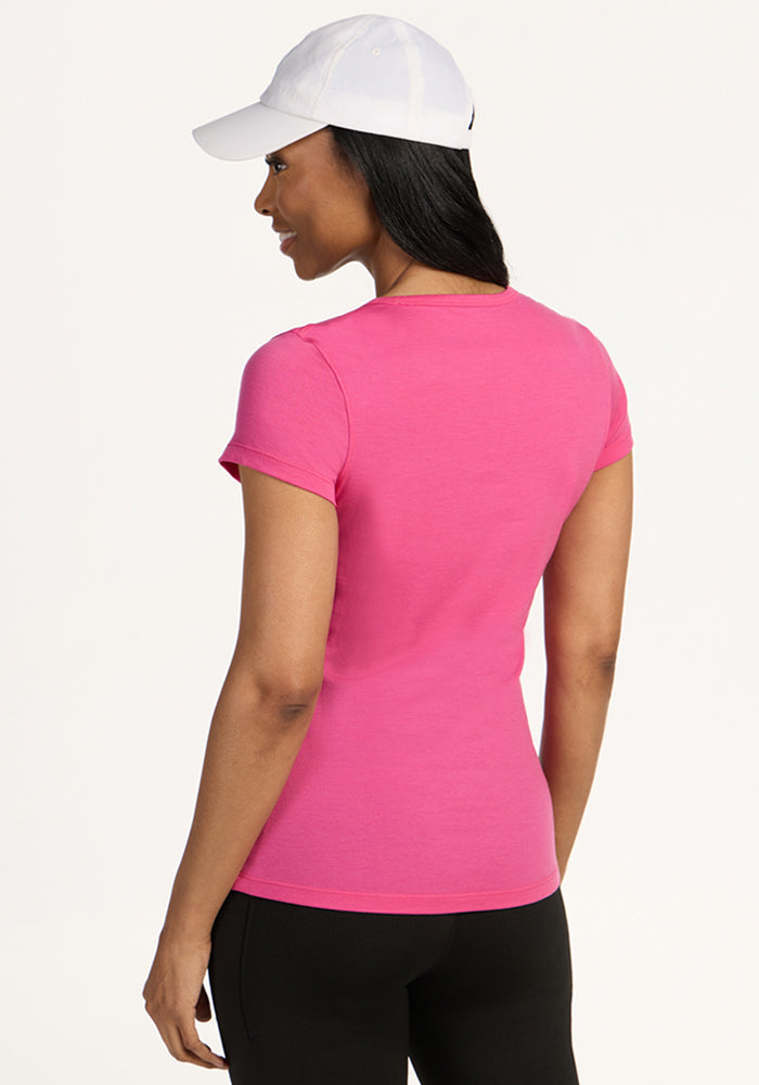 Woman faces away in a white cap and Woolx Addie Crew Neck—Final Sale in Raspberry Fizz.