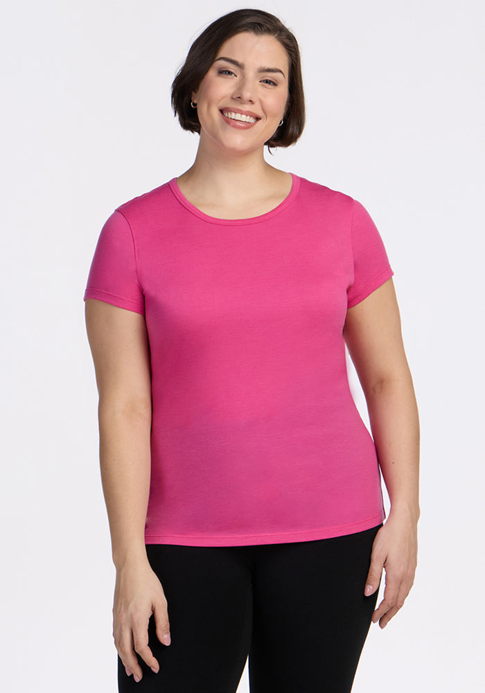 Smiling person in a Woolx Addie Crew Neck in Raspberry Fizz with black pants, on a plain white background.