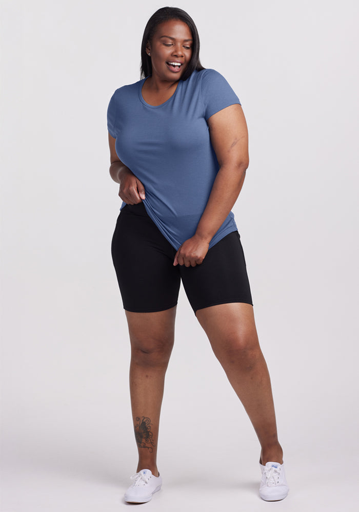 Woman in Woolx Addie Crew Neck - Skyline and black shorts smiles while standing, wearing white sneakers.