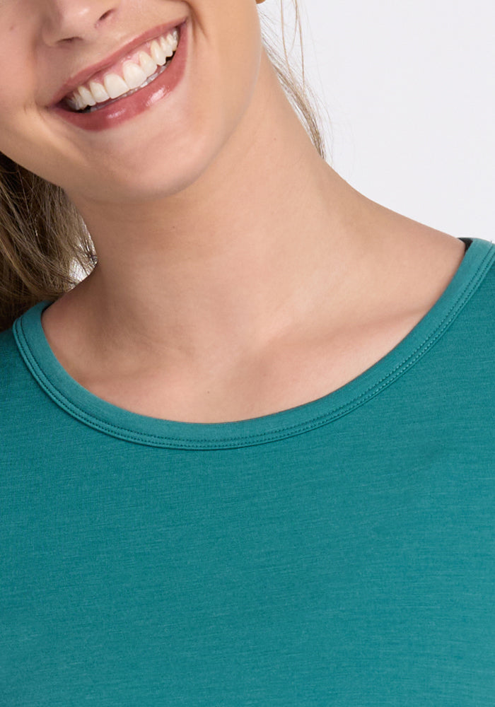 A smiling person wears the Woolx Addie Crew Neck in Surfside, shown from lips to upper chest and shoulders.
