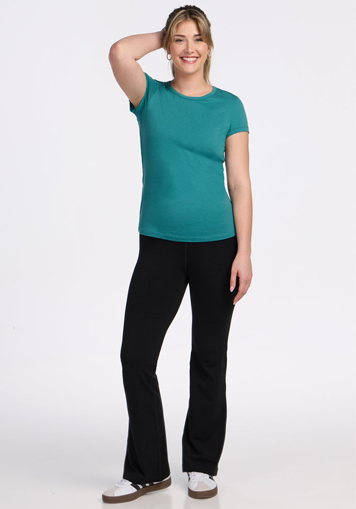 Woman smiling in a Woolx Addie Crew Neck • Final Sale - Surfside tee, black pants, and white sneakers.