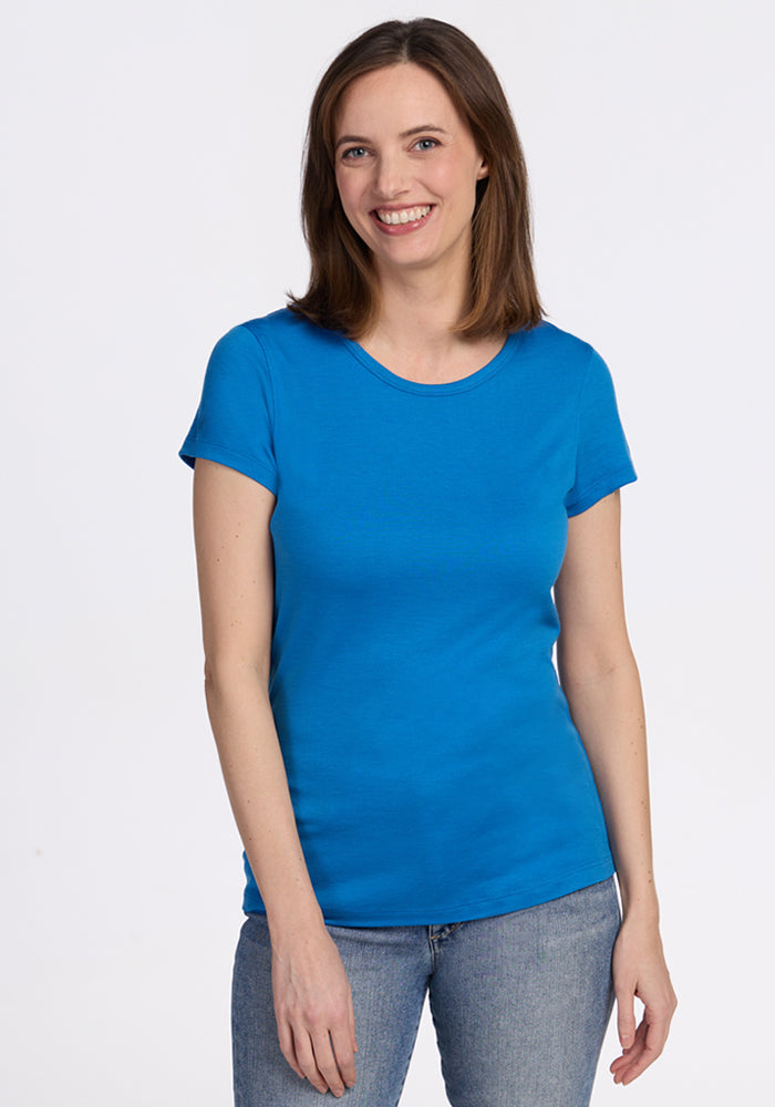 Smiling woman with straight brown hair wears Woolx Addie Crew Neck in Wave Rider, against a plain white background.