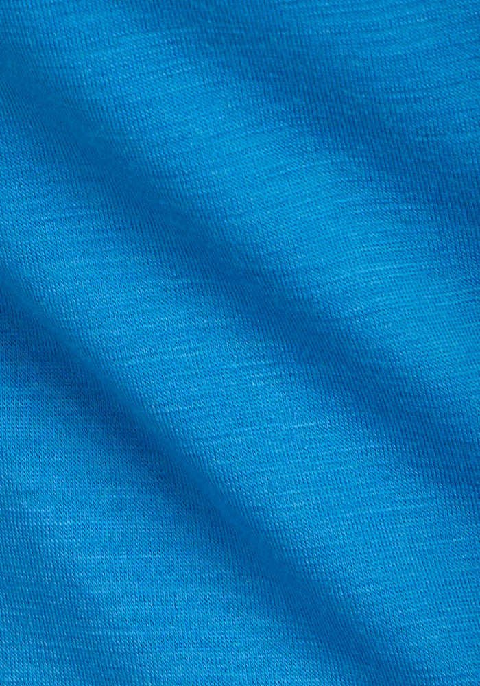 Close-up of Woolx Addie Crew Neck in Wave Rider, showing blue moisture-wicking fabric with textured, diagonal folds.