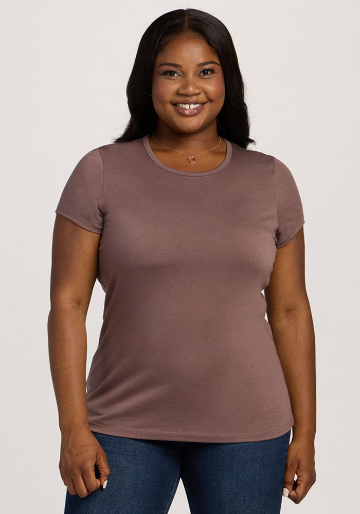 A woman in a Woolx Addie Crew Neck - Peppercorn shirt and jeans smiles at the camera against a plain background. | Sapphire is 5’8”, wearing a size XL