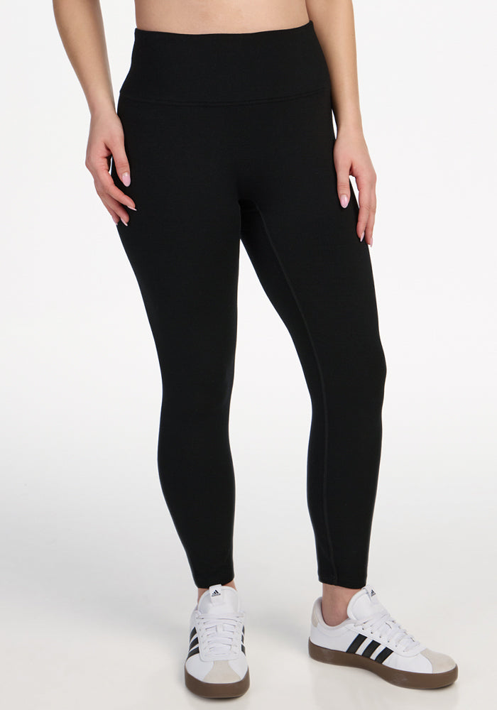 The image shows a person’s lower torso and legs against a white background, wearing Woolx Angela Leggings - Black and white Adidas sneakers with black stripes. | Ariana is 5'11", wearing a size S