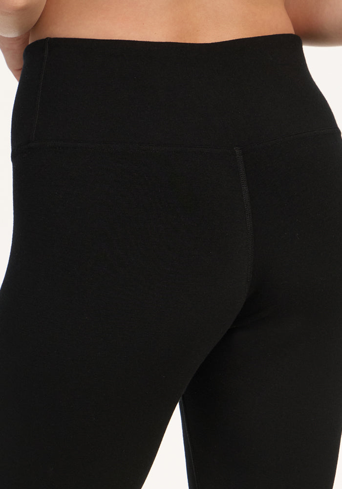 Close-up of a person wearing Woolx Angela Leggings - Black, highlighting the high waistband and upper leg area against a plain, light background.