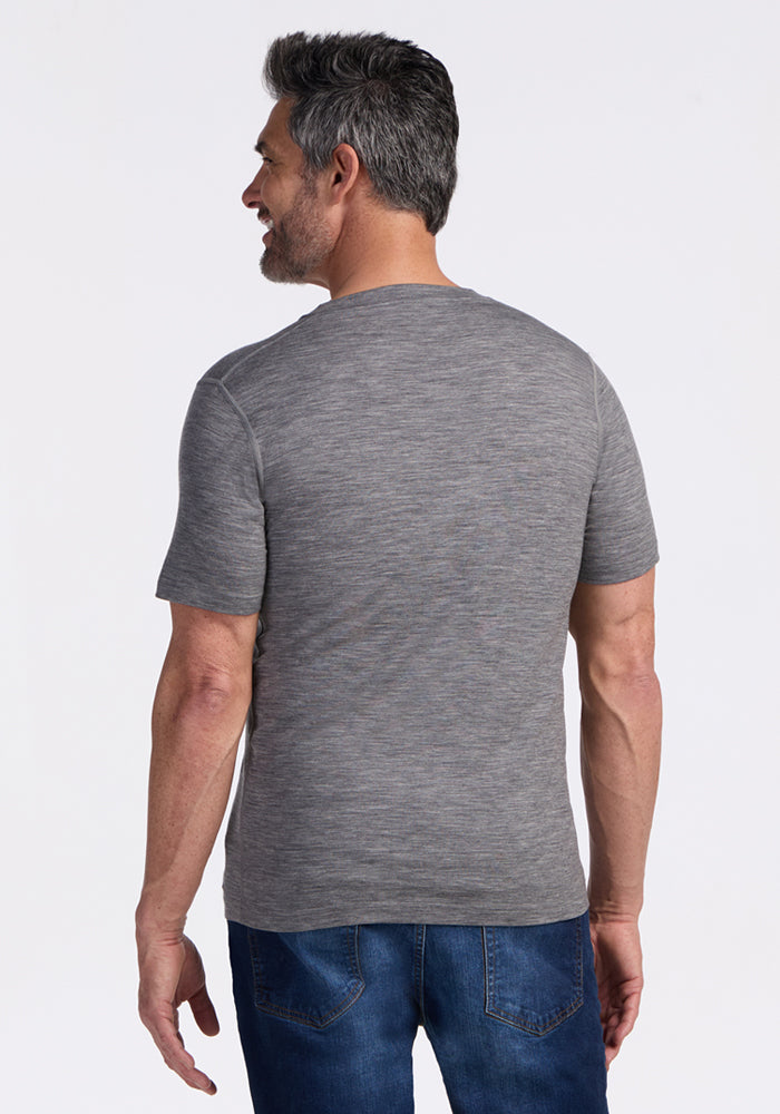 A man with short gray hair and a beard, seen from behind, wears the Woolx Ashton V Neck in Graphite Heather and blue jeans against a plain white background.