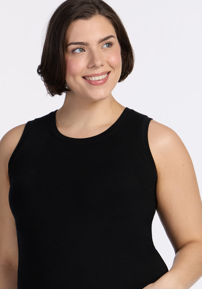 A woman with short brown hair and light skin smiles while looking to the side, wearing the Woolx Ava Tank Top in black against a plain, light background.