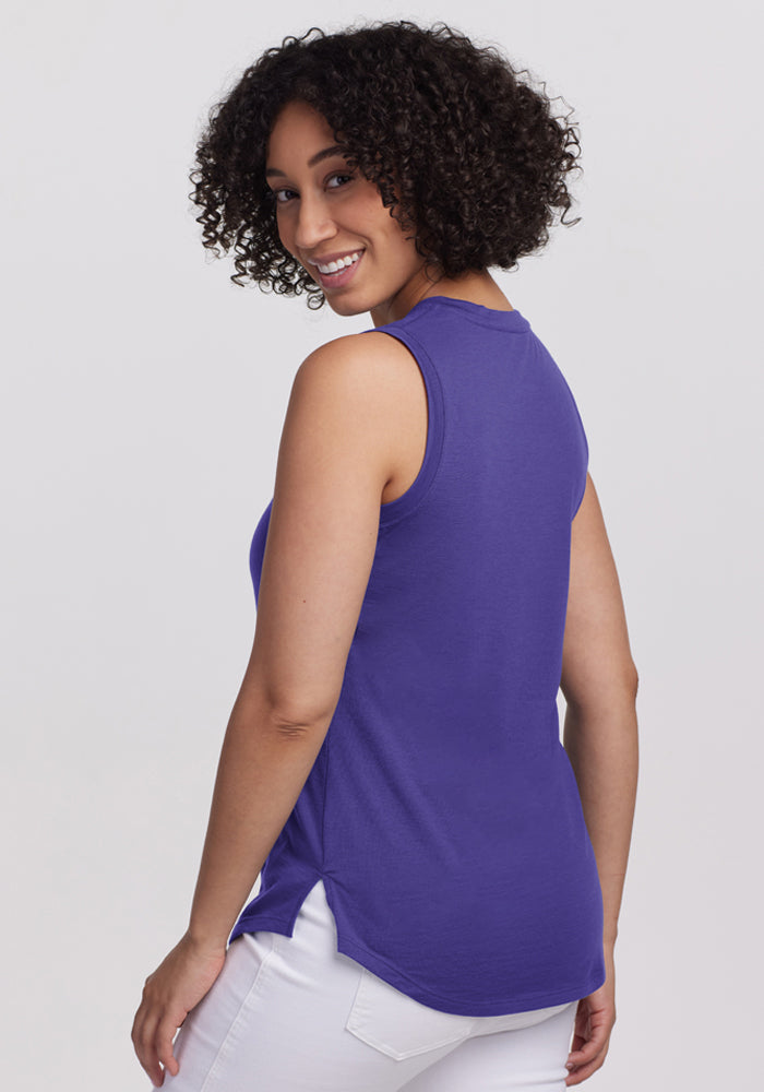 Smiling over her shoulder, a woman with curly hair wears the Woolx Bella Tunic Top - Berry Indigo against a plain background.