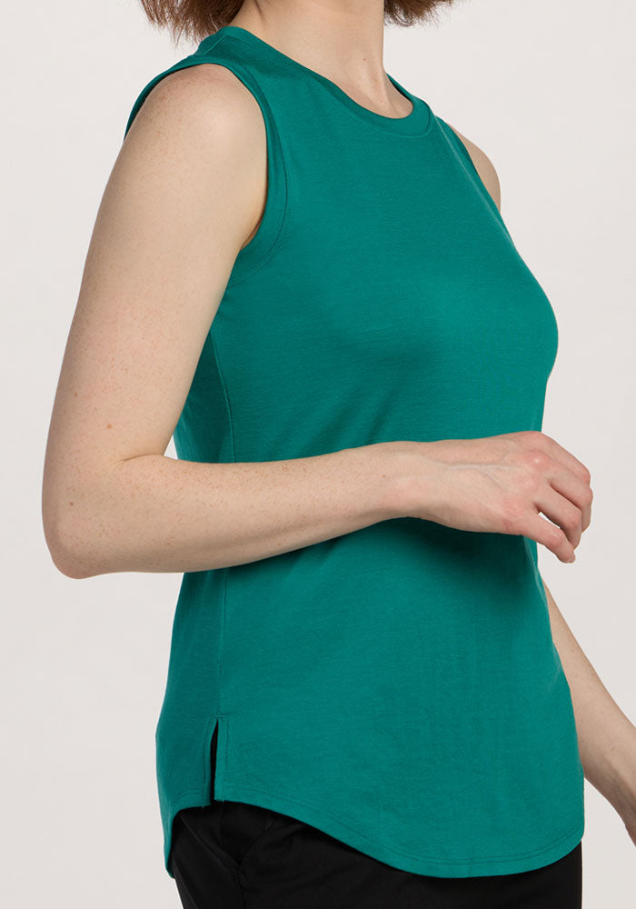A woman wears the Woolx Bella Tunic Top in Cabana Crush with black pants, standing against a plain light background.
