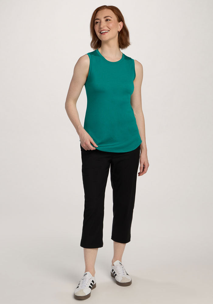 Woman wearing Woolx Bella Tunic Top - Cabana Crush, black capri pants, and white sneakers, standing and smiling.