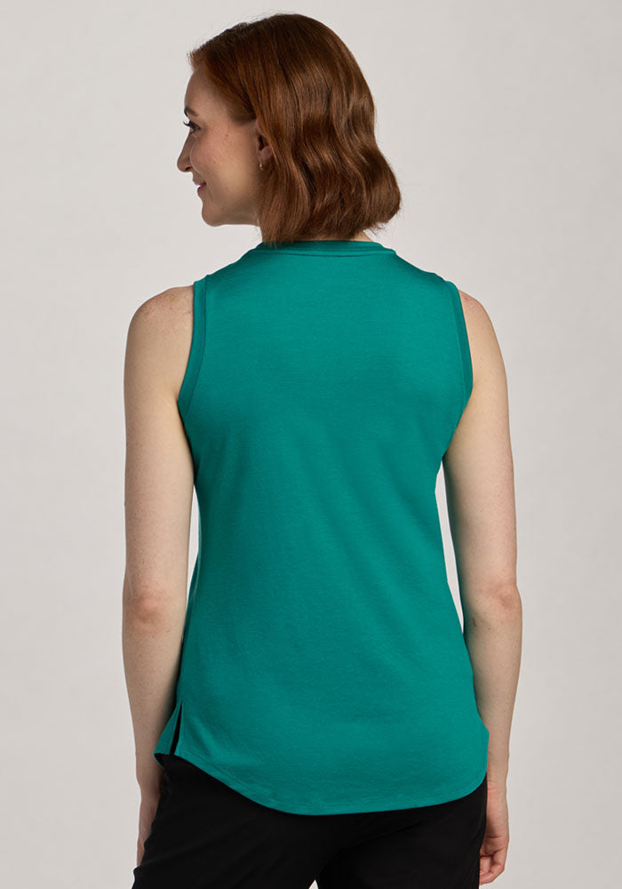 A woman with short brown hair wears a Woolx Bella Tunic Top in Cabana Crush and black pants, facing away from the camera.
