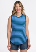A smiling woman with wavy blonde hair wears the Woolx Bella Tunic Top in Coastal Stripe and dark denim shorts, standing against a plain white background. | Ariana is 5'11", wearing a size S