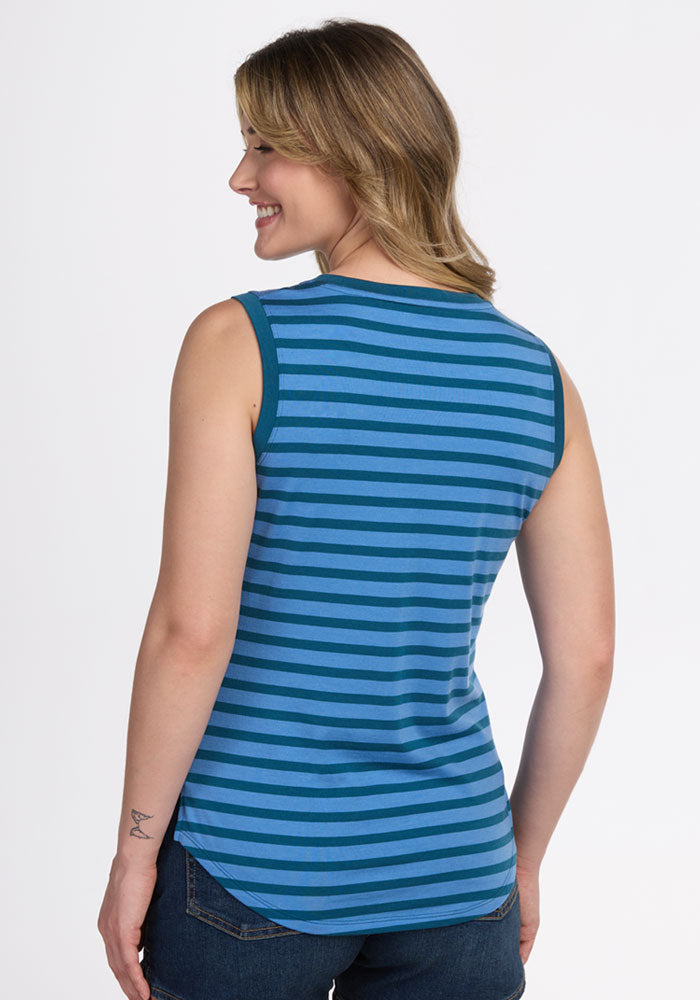 A woman with shoulder-length light brown hair smiles while facing away, wearing the Woolx Bella Tunic Top – Coastal Stripe with dark jeans; a small tattoo is visible on her left forearm.