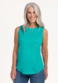 Smiling woman in a Woolx Bella Tunic Top • Final Sale - Cool Jade and blue jeans, against a plain background.