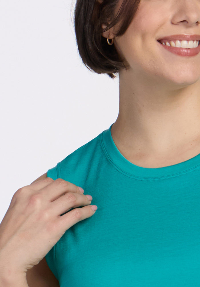 A woman in a Woolx Bella Tunic Top in Cool Jade smiles with dimples, one hand resting on her shoulder.