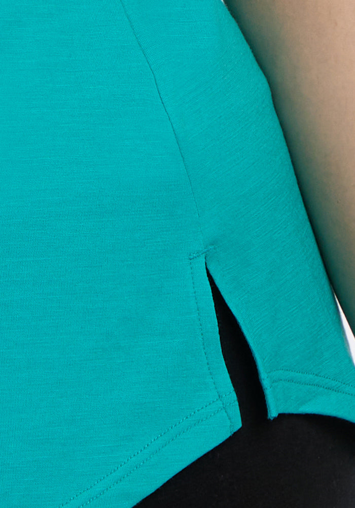 Close-up of Woolx Bella Tunic Top in Cool Jade, featuring a side slit, shown with black pants. Final Sale.