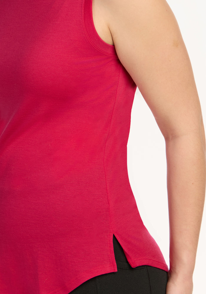 A woman wears the Woolx Bella Tunic Top in Poppy Spark, a sleeveless summer tank with a side slit, shown shoulder to hip.