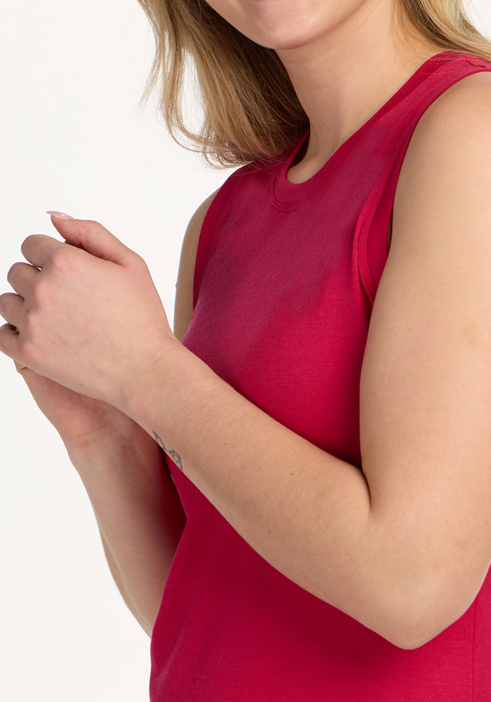 Woman in a Woolx Bella Tunic Top, Poppy Spark, sleeveless, arms crossed; shown from shoulders to mid-torso.