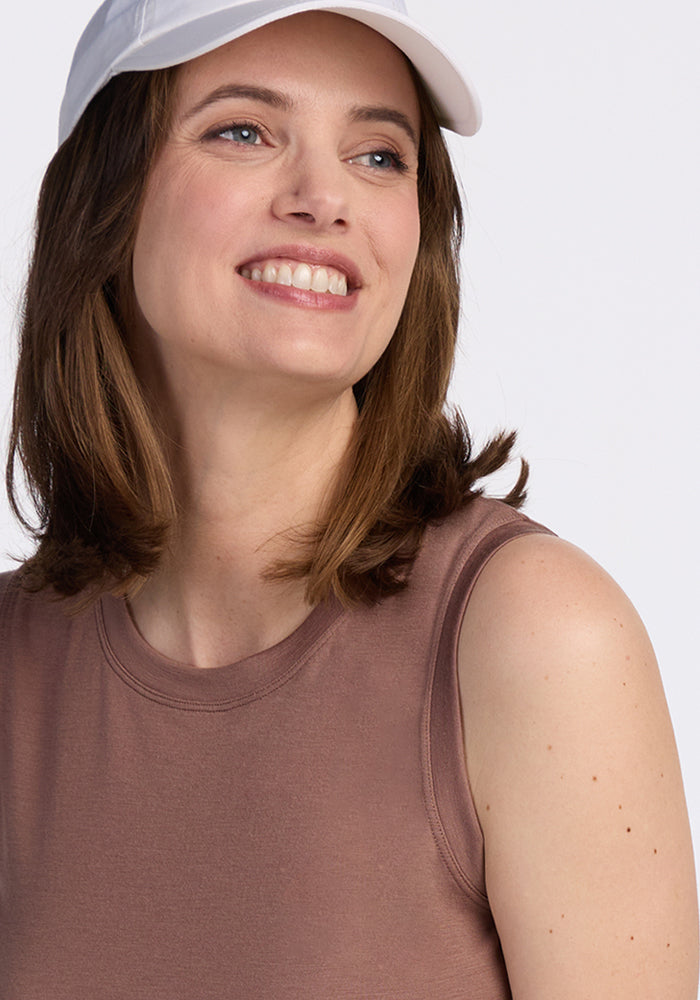 Smiling woman in a Bella Tunic Top • Final Sale - Sienna Kiss by Woolx, white cap, looking to the side.