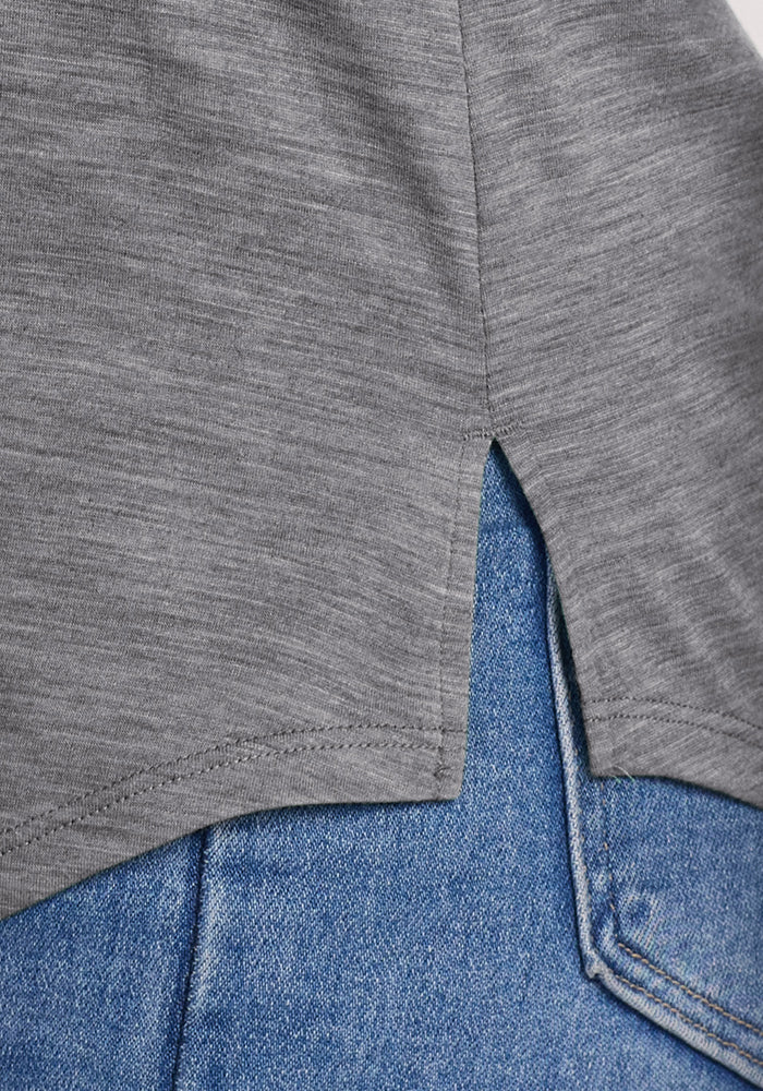 Close-up of the hem on the Woolx Bella Tunic Top in Graphite Heather, a lightweight summer style with a small side slit, worn over blue denim jeans.