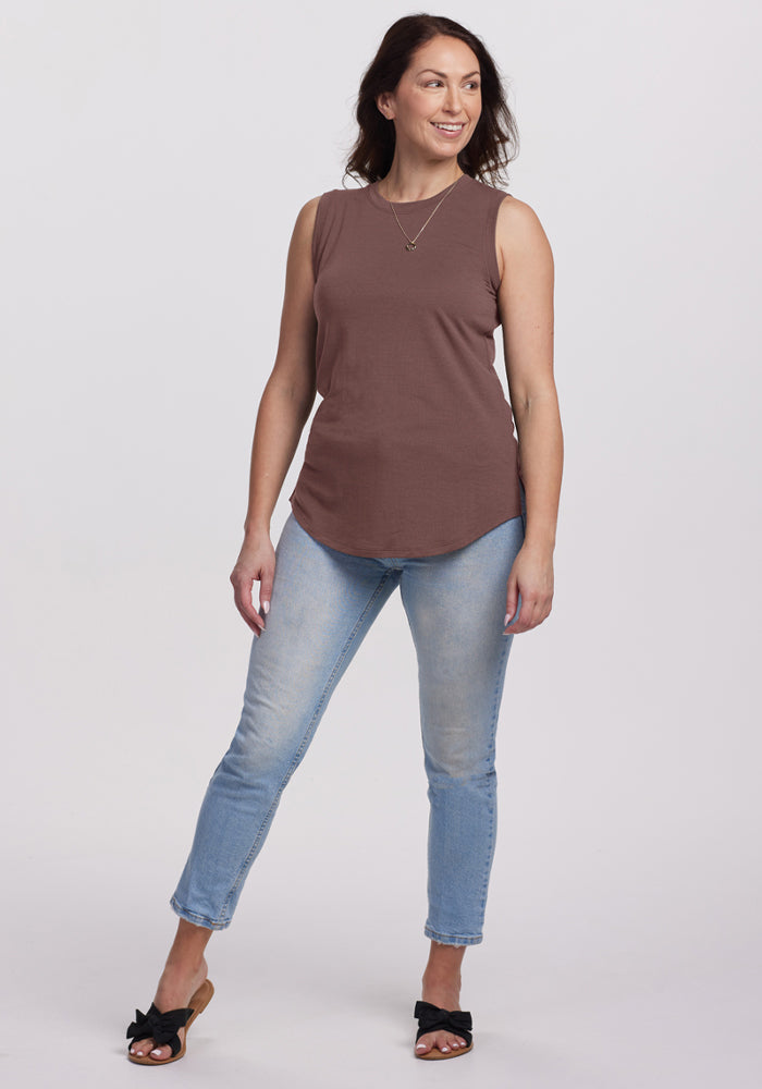 Woman in a Woolx Bella Tunic Top in Peppercorn, light blue jeans, and black sandals smiles against a white background.
