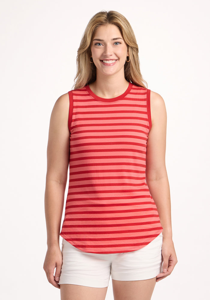 A woman with long blonde hair smiles at the camera wearing the Woolx Bella Tunic Top in Wildberry Stripe and white shorts, standing against a plain white background. | Ariana is 5'11", wearing a size S