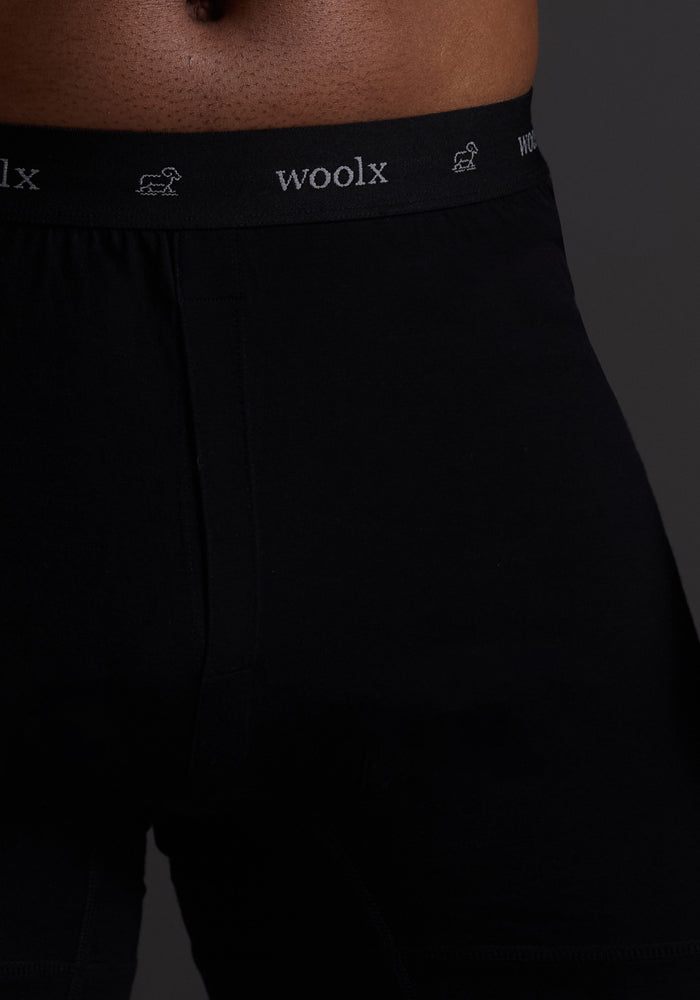 Close-up of someone wearing Woolx Breathe Boxer Shorts in black, featuring a waistband with "woolx" in light text on a dark background. Made from Australian Merino wool, these seamless boxers offer superior breathability and softness with no visible patterns.