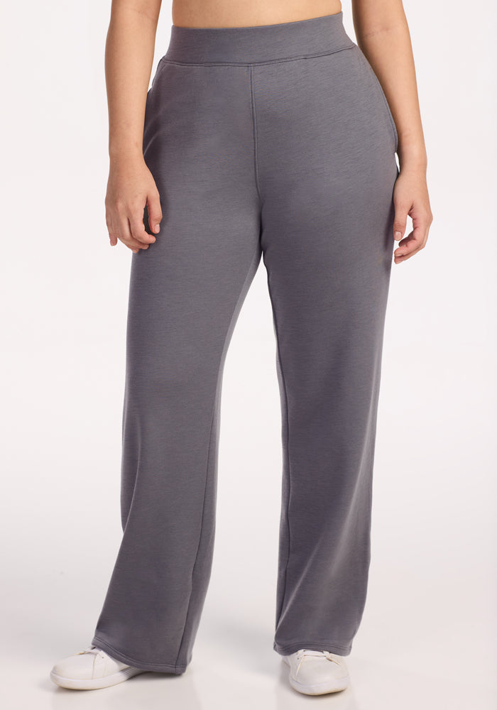 A person models Woolx Bree Lounge Pants • Final Sale - Arctic Dusk, a women’s loose fit Merino wool pant in gray, standing with hands by their sides and wearing white sneakers against a plain white background.
