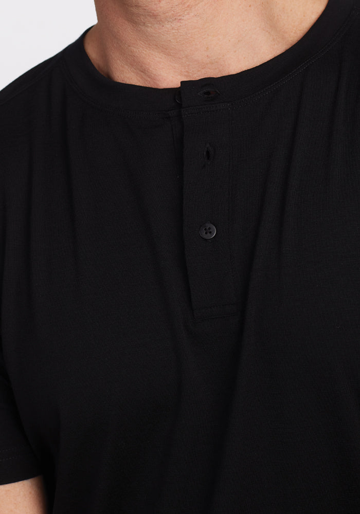 A person wearing the Bronx Henley - Black by Woolx, crafted from soft Merino wool. The shirt has a short button placket with two black buttons and the fabric looks exceptionally comfortable. The close-up shot of the chest and part of the collar highlights its Woolmark-certified quality.