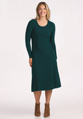 A woman smiles against a light background, wearing the Woolx Caroline Ribbed Twirl Dress in Deep Timber with brown ankle boots. | Ariana is 5'11", wearing a size S