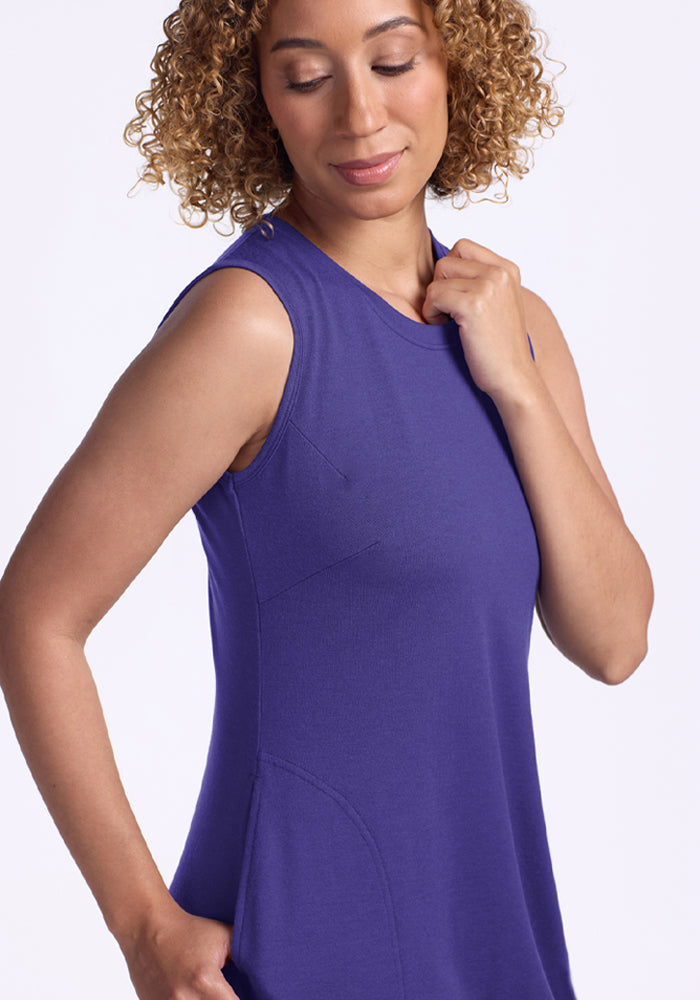 Woman with curly hair in the Woolx Cassie Dress - Berry Indigo, looking down and touching her shoulder.