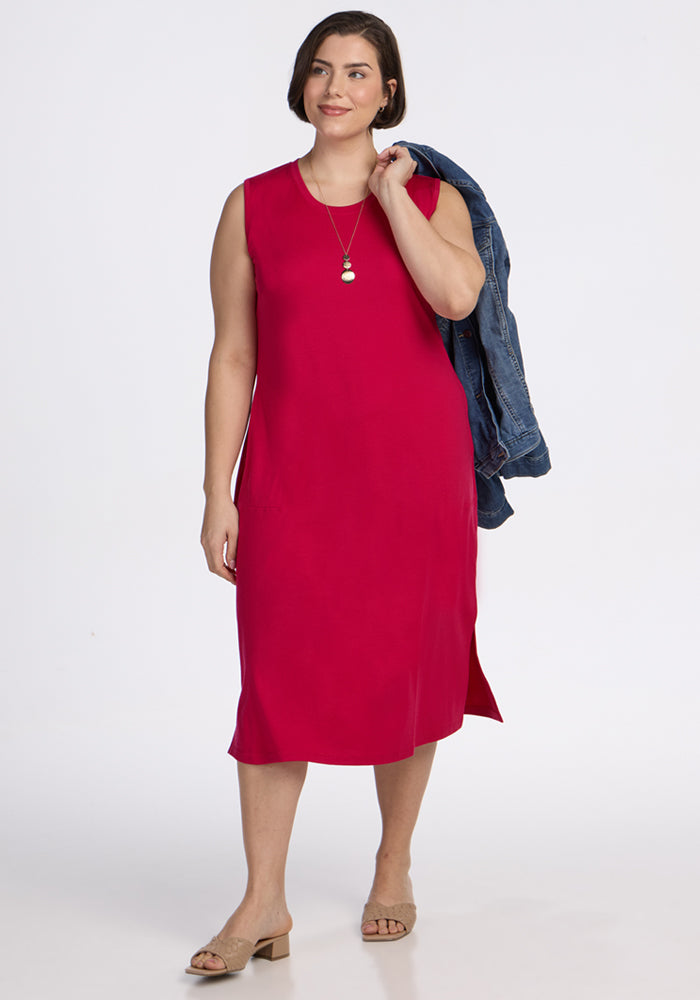 Woman in a Woolx Cassie Dress • Final Sale - Poppy Spark, holding a denim jacket, with sandals and a necklace.
