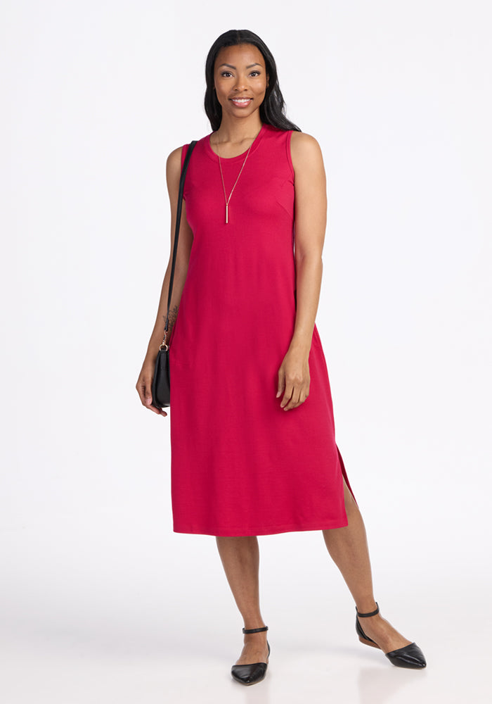 Woman smiles at the camera wearing the Woolx Cassie Dress in Poppy Spark, paired with black flats and a shoulder bag.