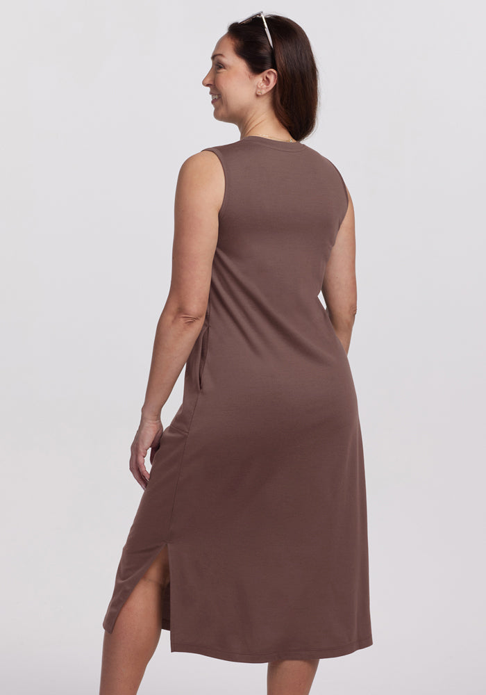 Woman in Woolx Cassie Dress - Peppercorn, standing with back turned, smiling, sunglasses atop her head.