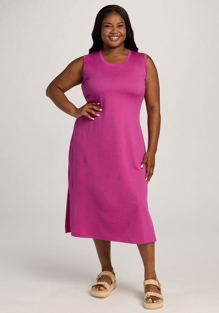 Smiling woman in the Woolx Cassie Dress - Summer Sorbet, sleeveless and knee-length, poses against a light background. | Sapphire is 5’8”, wearing a size XL