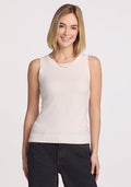 A person with shoulder-length blonde hair, wearing the Chessy Tank Top - Dewdrop Pearl by Woolx and dark pants, smiles at the camera. They sport layered necklaces while standing against a plain white background. | Georgia is 5’10”, wearing a size XS