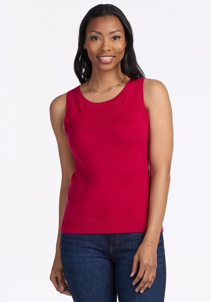 A woman with long dark hair smiles while wearing the Woolx Chessy Tank Top in Poppy Spark, paired with blue jeans and a gold necklace, standing against a plain white background. | Jade is 5’10”, wearing a size S