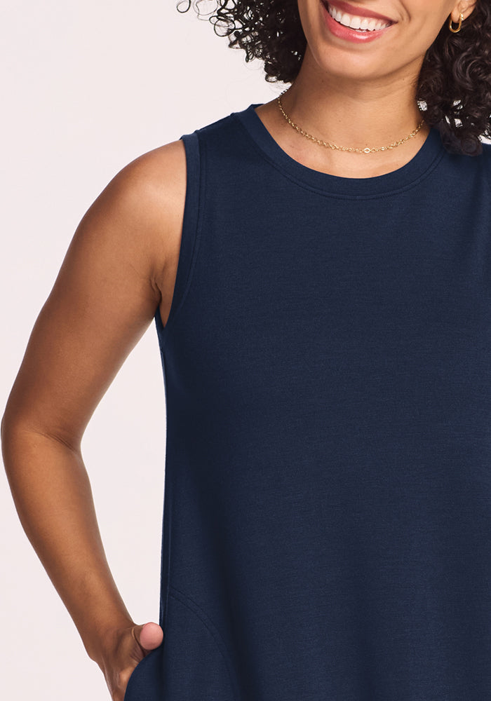 Woman smiling in the Woolx Clara Dress • Final Sale - Deep Navy, gold necklace, hand in pocket, with curly hair.