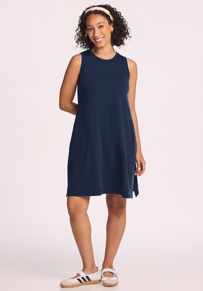 Smiling woman in Woolx Clara Dress • Final Sale - Deep Navy, white headband, and sneakers against a plain light background.