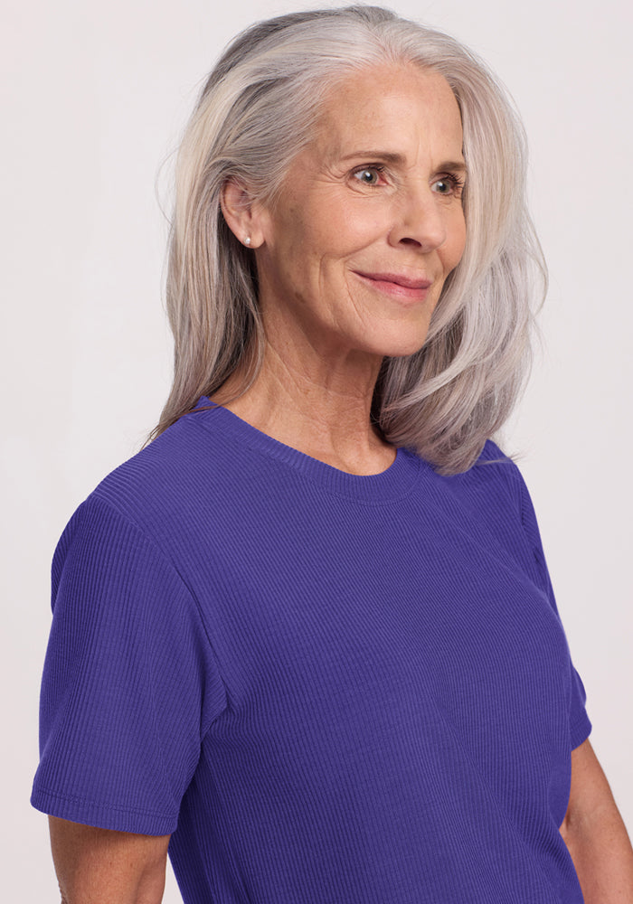 Smiling older woman in Woolx Delia Ribbed Short Sleeve - Berry Indigo, looking slightly to the side.