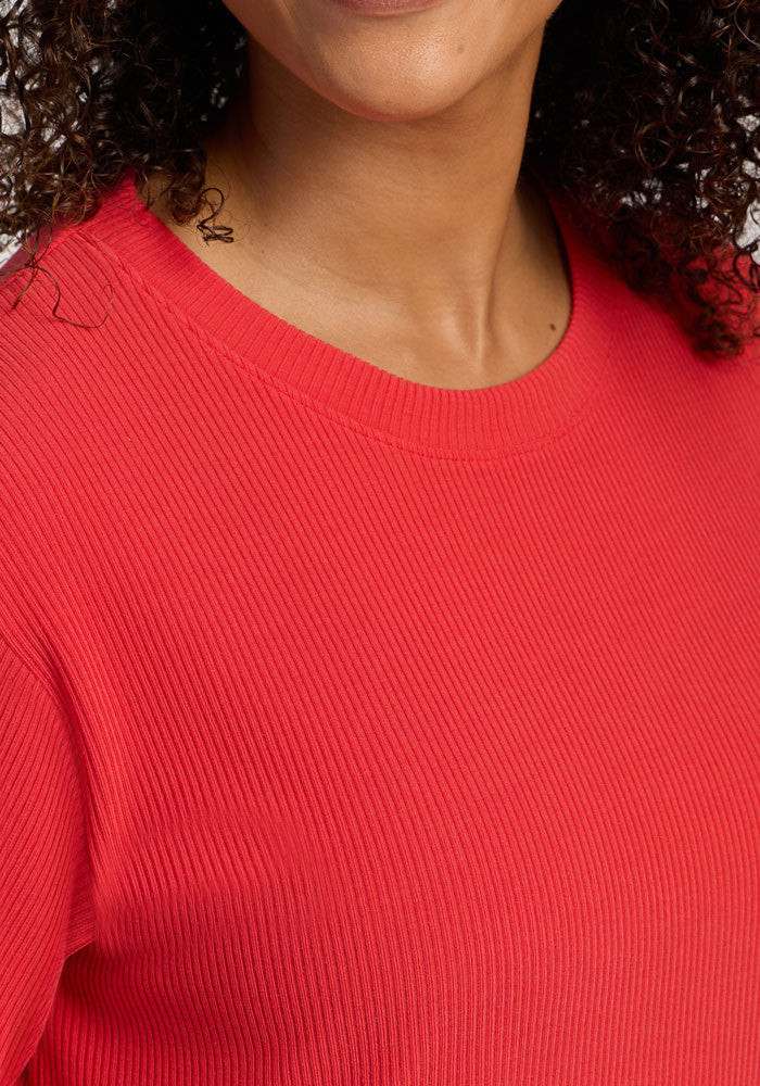 Close-up of a person smiling in the Woolx Delia Ribbed Short Sleeve - Hibiscus; face partially visible.