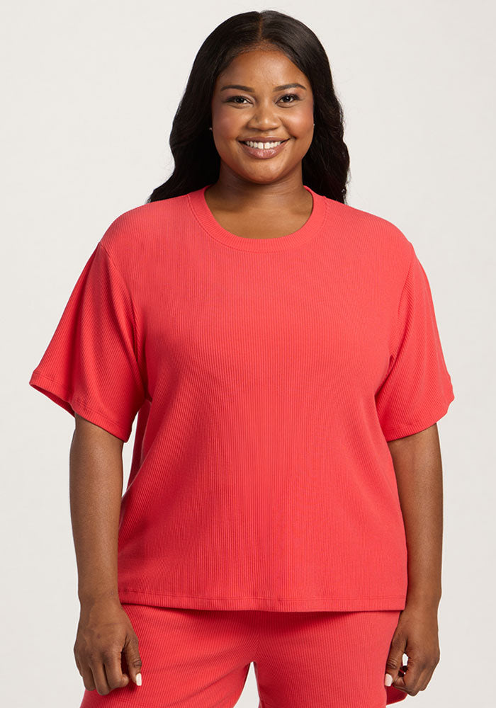 Smiling woman wears Woolx Delia Ribbed Short Sleeve in Hibiscus, paired with matching pants, against a plain background. | Sapphire is 5’8”, wearing a size XL