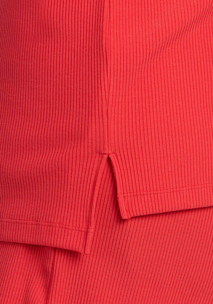 Close-up of the Woolx Delia Ribbed Short Sleeve - Hibiscus, showing ribbed merino fabric and small side slit detail.