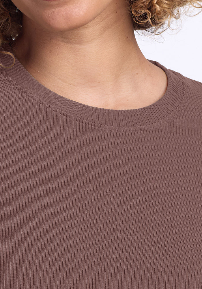 Close-up of a person in the Woolx Delia Ribbed Short Sleeve in Peppercorn; neck and curly hair partly visible.