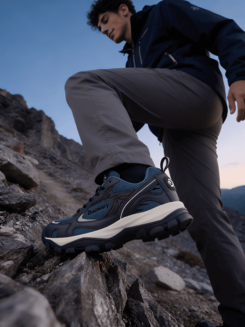 Person wearing blue hiking shoes on a rocky mountain trail