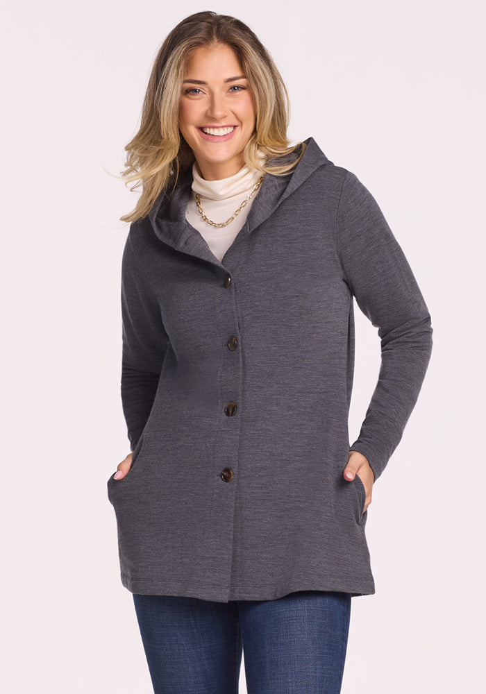Smiling woman in Woolx Edna Hooded Cardigan - Cinder Melange, white top, and jeans with hands in pockets.